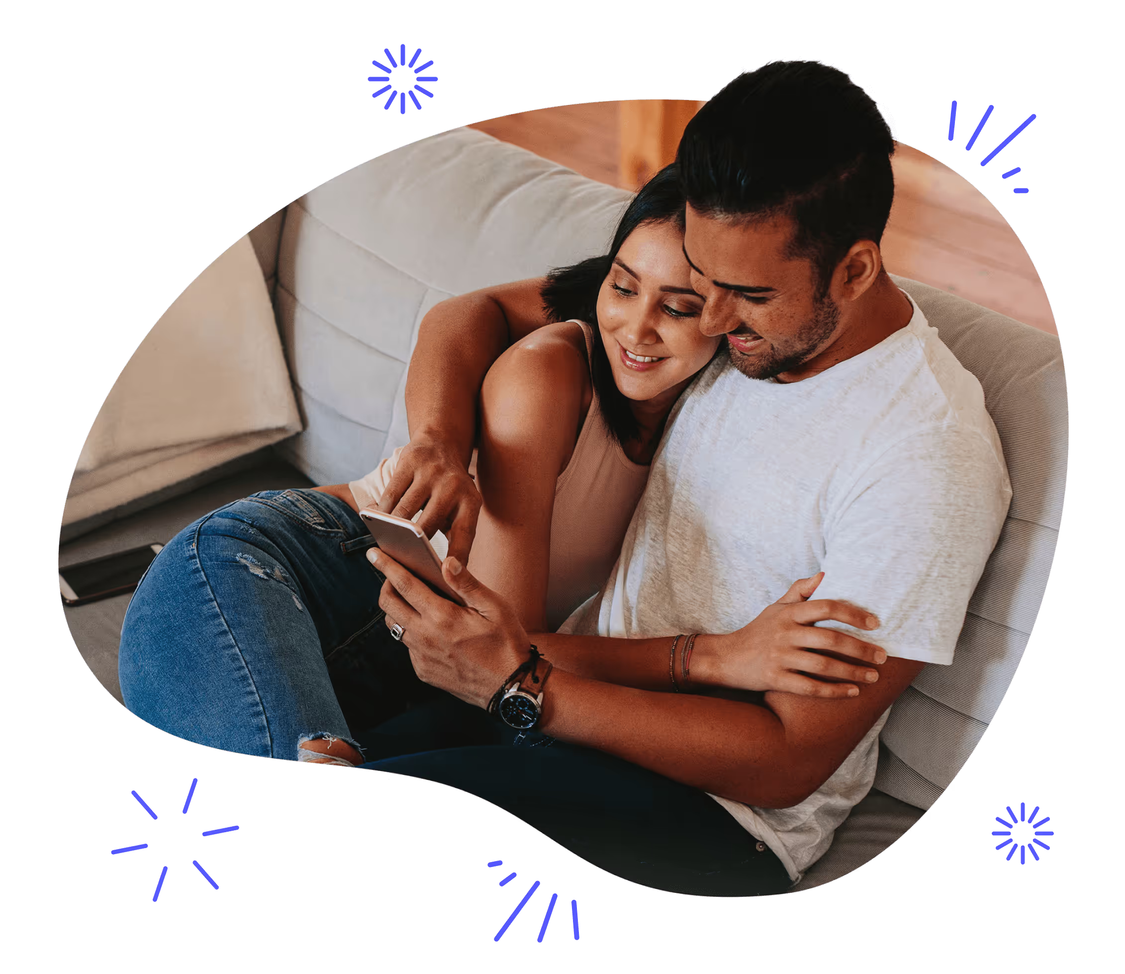 A couple cuddling on a couch looking at a phone together